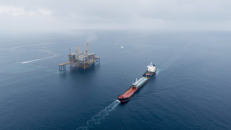 Vue aérienne réaliste de la mer du Nord au large du Danemark, avec une plateforme offshore et un navire transportant du CO2 liquéfié sous une lumière froide.